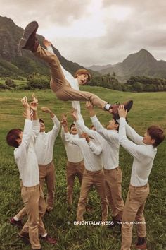 a group of young men standing next to each other on top of a lush green field