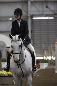 a woman riding on the back of a white horse