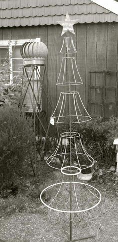 a metal christmas tree in front of a building with a star on it's top