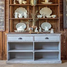 an old china cabinet with plates and cups on it