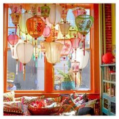 a living room filled with lots of different colored lanterns hanging from the ceiling next to a window