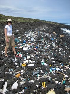 a woman standing on top of a rocky beach covered in plastic bottles and other trash