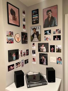 a white table topped with speakers and pictures on the wall next to a record player