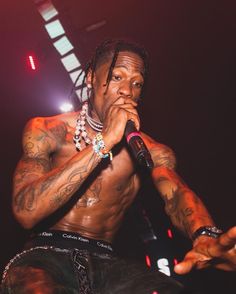 a man with tattoos on his chest holding a microphone