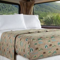 there is a bed with a blanket on top of it and mountains in the background