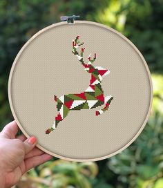 a hand holding up a cross stitched deer