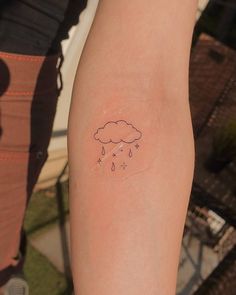 a person with a small tattoo on their arm that has a cloud and rain coming out of it