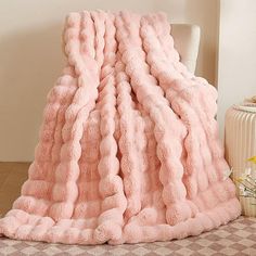 a pink blanket sitting on top of a white chair