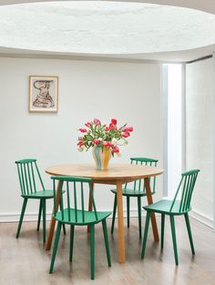 a dining room table with four chairs and a vase filled with flowers on top of it