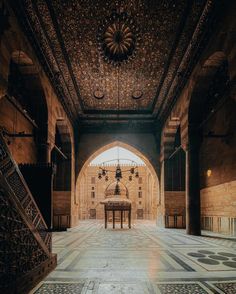 the inside of an ornate building with stairs leading up to it and a table in the middle