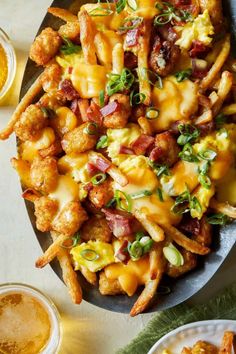 a plate filled with cheesy tater tots covered in cheese and bacon