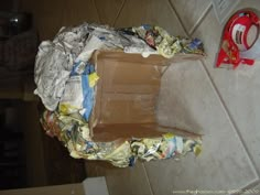 an open cardboard box sitting on top of a tiled floor next to a red object