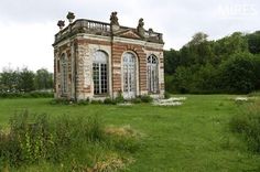 an old brick building sitting on top of a lush green field