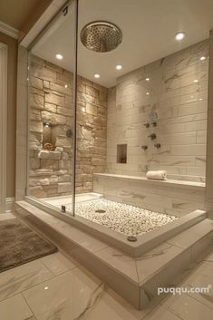 a large bathroom with a stone wall and glass shower stall, along with a rug on the floor