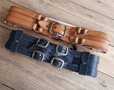 two leather belts sitting on top of a wooden floor next to each other with buckles