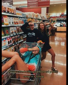 two people standing next to each other near a shopping cart in a store with one person laying on the floor