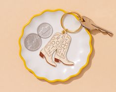 a white plate topped with a pair of boots and two pennies next to a keychain