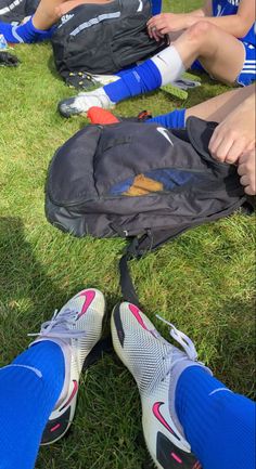 the soccer players are sitting on the grass with their backpacks in front of them