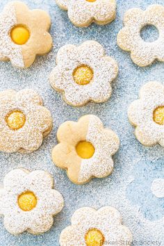 some sugar cookies with yellow centers are on a blue surface