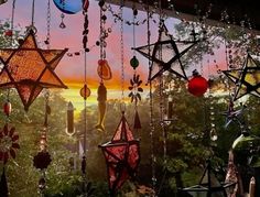 the sun is setting in the sky behind many hanging ornaments and glass bottles with stars on them