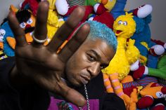 a man with blue hair is holding his hand up in front of stuffed animals