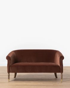 a brown couch sitting on top of a hard wood floor next to a white wall