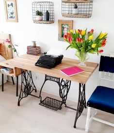 a room with a sewing machine and flowers on the table