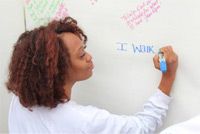 a woman writing on a whiteboard with marker