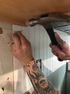 a man with a tattoo on his arm working on a wall