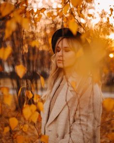 a woman standing in front of some yellow leaves