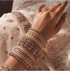 a close up of a person's hands wearing bracelets and rings on their fingers