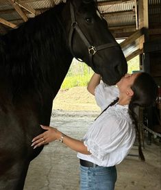 a woman standing next to a black horse