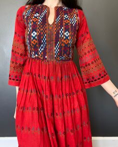 1970s Afghan dress. *Red floral printet cotton fabric  *Embroidered yoke. *The dress is unlined. *Zipper down the back. *Used vintage condition. Has a small stain on the skirt (see picture) and some darker discoloration on the front near the waistline (see picture) Such a beautiful dress but shows signs of age and wear. ERA: 1970s or earlier LABEL: None. Made in Pakistan SIZE: XS  (Please check measurements) FABRIC: Cotton Measurements are taken flat and must be doubled: Chest: 43 cm x 2 Waist: Fitted Cotton Dress With Geometric Embroidery, Fitted Folk Style Cotton Dress, Fitted Folk Cotton Dress, Fitted Cotton Folk Dress, Cotton Midi-length Embroidered Dress With Floral Print, Cotton Embroidered Midi Dress With Floral Print, Fitted Folk Style Embroidered Cotton Dress, Red Folk Style Floral Print Dress, Bohemian Embroidered Fitted Dress For Fall