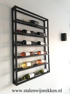 a wall mounted wine rack filled with lots of bottles on top of a white wall