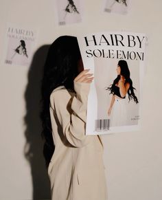 a woman standing in front of a wall holding up a hair by solemon magazine