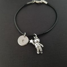 "Personalized Waxed Cord Bracelet! An astronaut charm on a black waxed cord makes the perfect gift for your loved one. The detailed astronaut bracelet charm is made from zinc alloy and measures 15 x 22 mm. The charm is not reversible. The bracelet is a waxed braided rope and measures 7.25\" with a 1-2\" extender. The lobster clasp is zinc alloy. The black cord bracelet can be personalized with a .5\" silver plated disc stamped with the initial of your choice. Each personalized bracelet arrives i Adjustable Black Bracelets With Charms, Adjustable Moon Charm Bracelet, Minimalist Adjustable Chain Bracelet With Charms, Adjustable Minimalist Chain Bracelet With Charms, Celestial Bracelet, Bracelet Cord, Moon Bracelet, Black Bracelet, Personalized Bracelet