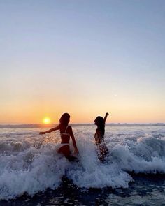 two people in the water at sunset on surfboards