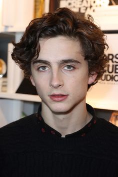 a young man with curly hair wearing a black sweater