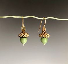 "Since ancient times the acorn has been a symbol of luck, prosperity, youthfulness, and power. It also represents spiritual growth and perseverance. Theses charming acorn earrings are hand-sculpted by melting and shaping glass rods in a propane/oxygen torch flame. Layering different colors of molten glass creates beautiful and natural-looking color gradations in the nut and in the spots on the cap. They measure about 1/2\" by 7/8\" and are suspended from your choice of sterling silver or gold-fi Acorn Earrings, Halloween 2, Pyrex Glass, Ancient Times, Glass Sculpture, Spiritual Growth, Ear Wires, Art Glass, Types Of Metal