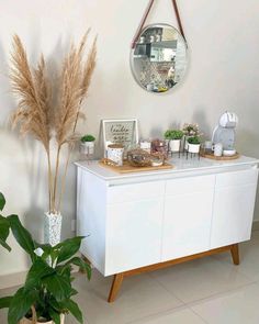 a white dresser sitting next to a potted plant