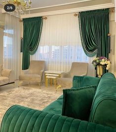 a living room filled with green velvet couches and chairs next to a chandelier