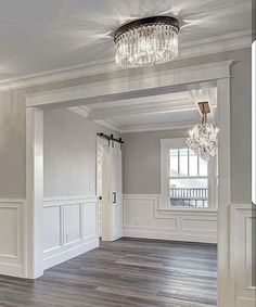 an empty room with wood floors and chandelier