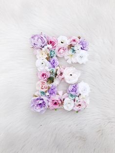 the letter e is made up of flowers on a white furnishing area with a fuzzy background