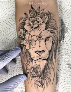 a lion with flowers on it's head is shown in this tattoo artist's hand