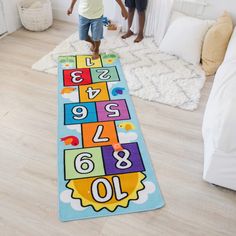 two children are playing on the floor in front of a rug with numbers and letters