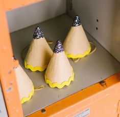 three yellow and silver cones sitting on top of a shelf