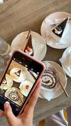 a person holding up a cell phone to take a photo of desserts on plates