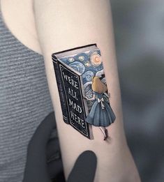 a woman's arm with a book tattoo that reads, we are all mad here