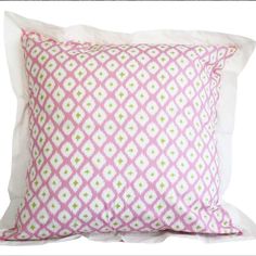 a pink and white pillow on top of a bed next to a pillow cover with green dots