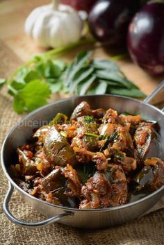 a pan filled with meat and vegetables on top of a wooden table next to onions